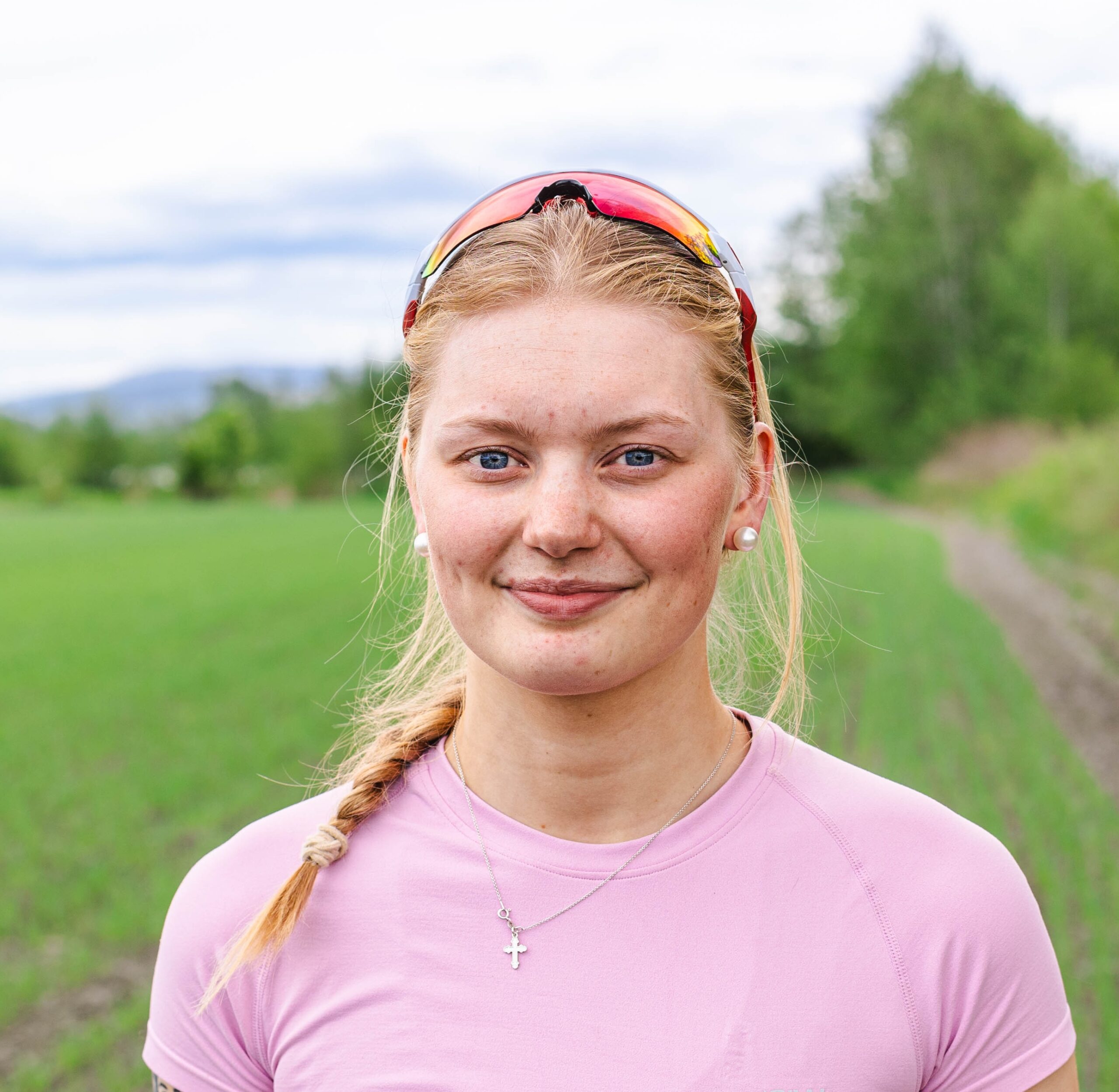 jente med blondt hår ute i natur med solbriller på hodet
